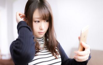 鏡で白髪を確認する女性